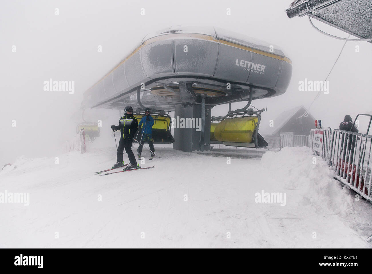 Skifahrer, der Sesselbahn auf dem Gipfel Der Berg Skrzyczne in Schnee auf einem nebligen Wintertag in Szczyrk ski resort in Polen Stockfoto