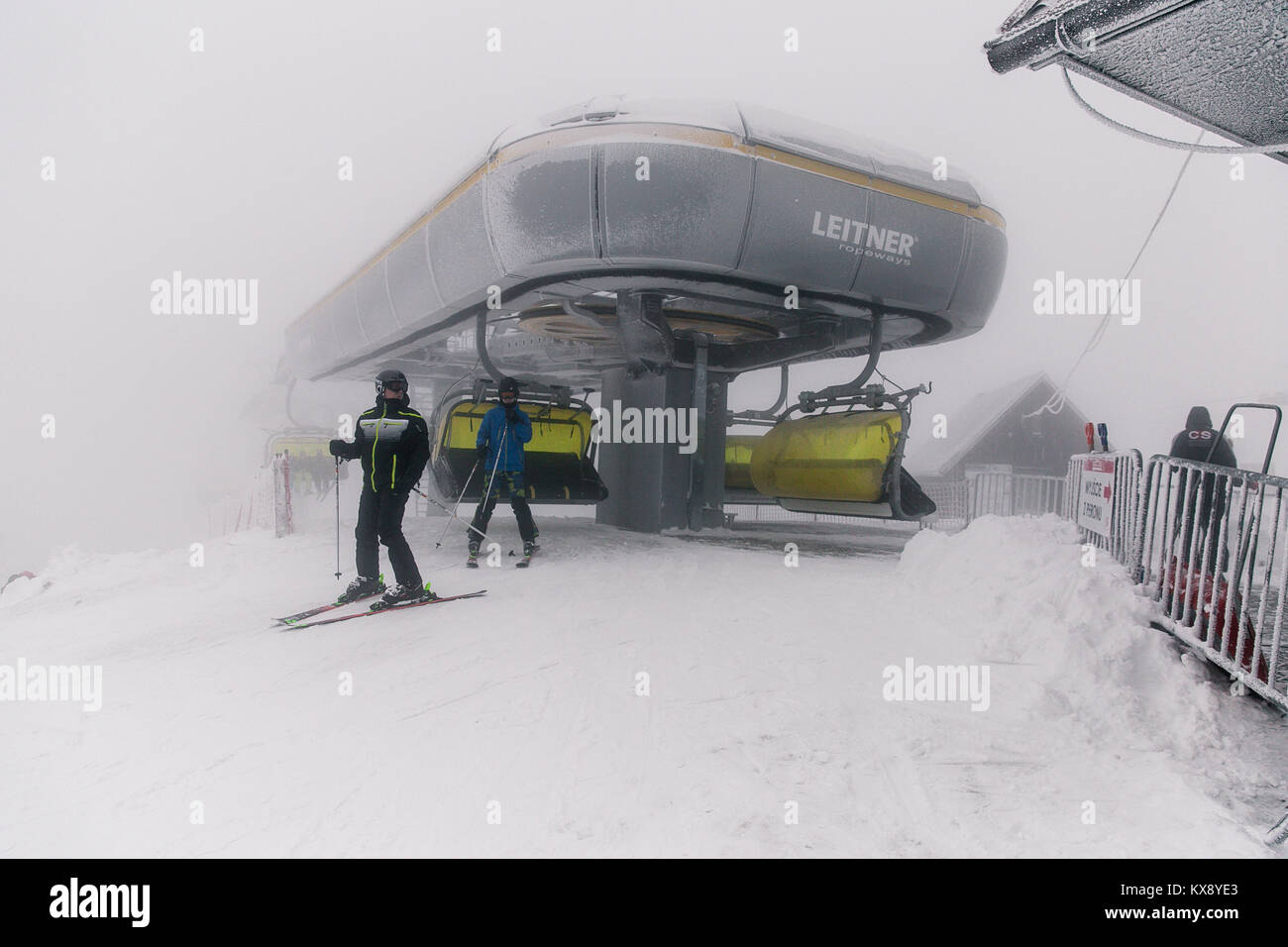 Skifahrer, der Sesselbahn auf dem Gipfel Der Berg Skrzyczne in Schnee auf einem nebligen Wintertag in Szczyrk ski resort in Polen Stockfoto