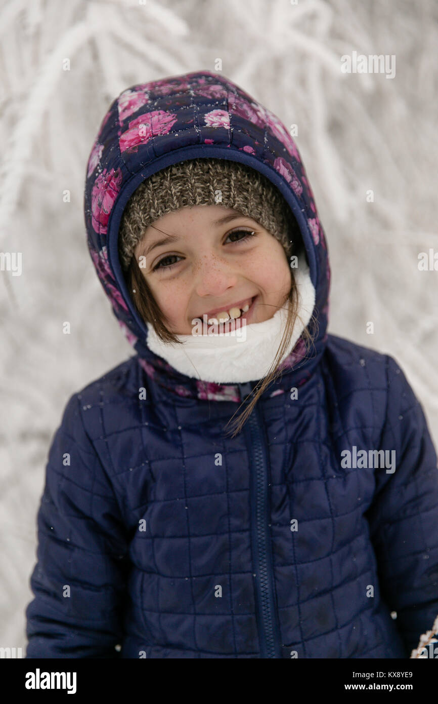 Junge 7 Jahre alt Happy girl Lächeln und Lachen bis in die warme Kleidung im Winter Schnee Landschaft kuschelten Stockfoto