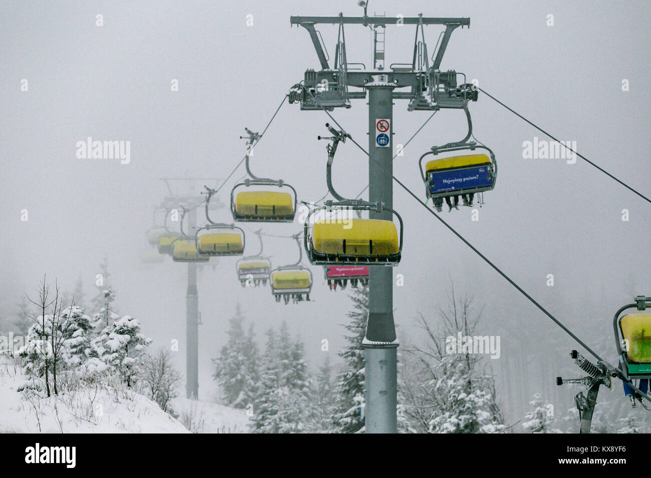Ski Sessellift bringt Skifahrer und Snowboarder auf den Berg Skrzyczne nach starker Schneefall auf einem nebligen Wintertag in Szczyrk ski resort in Polen Stockfoto