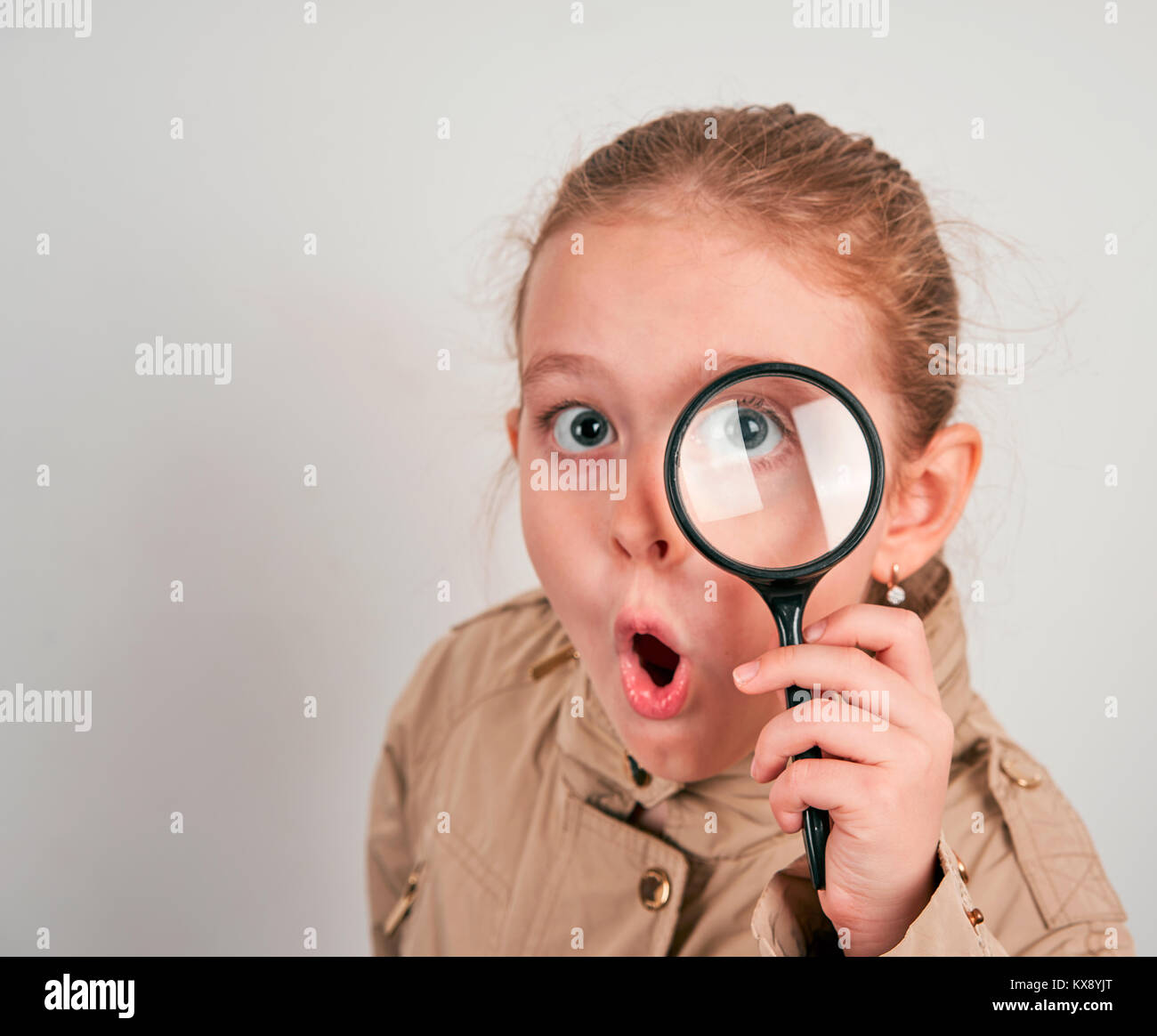Mädchen Detektiv mit Lupe in einen Regenmantel auf weißem Hintergrund Stockfoto