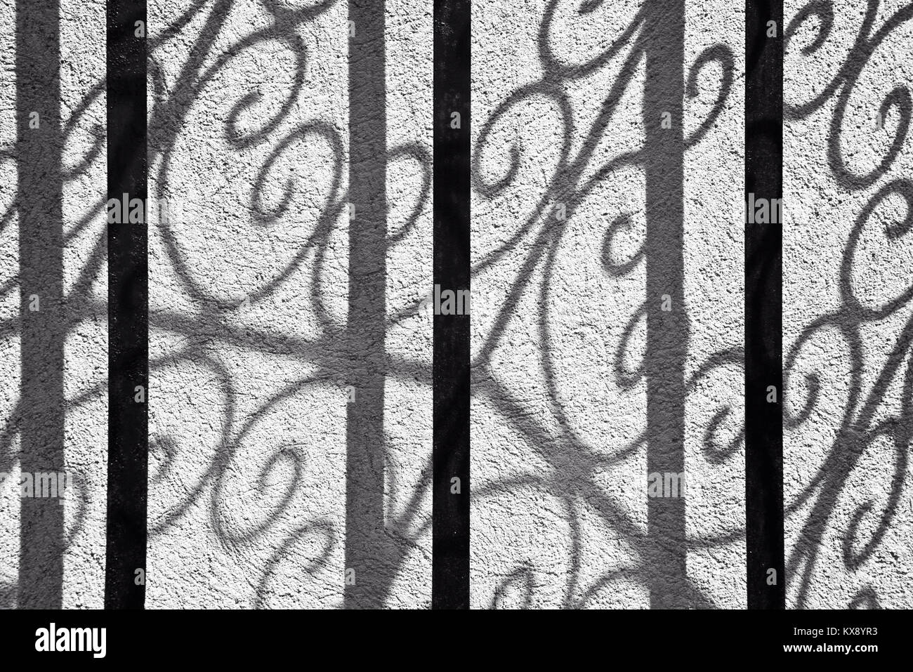 Abstrakte Schatten einer gekrümmten schmiedeeiserne Tür an einer Wand, die Schwarz-Weiß-Fotografie Stockfoto