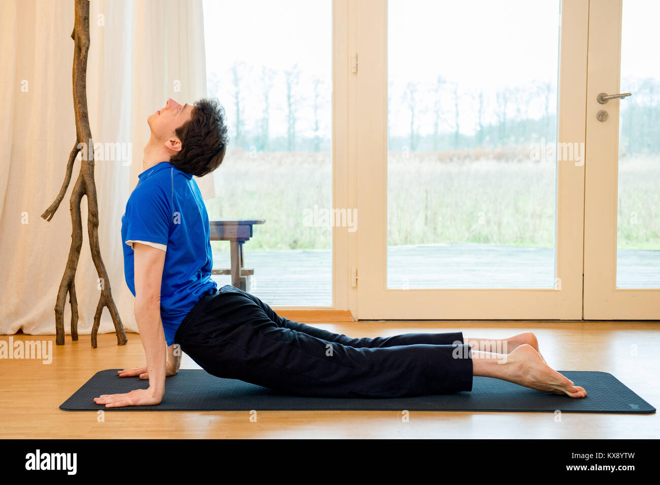 Man Yoga im Innenraum in einem Retreat Raum tun in den nach oben schauenden Hund pose-Urdhva Mukha Svanasana Stockfoto
