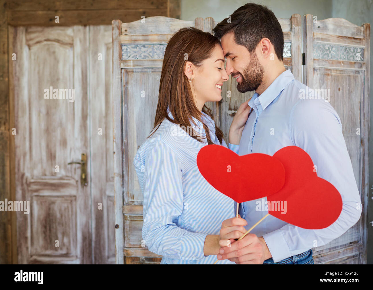 Das Paar Umarmungen mit Herzen in der Hand drinnen. Stockfoto