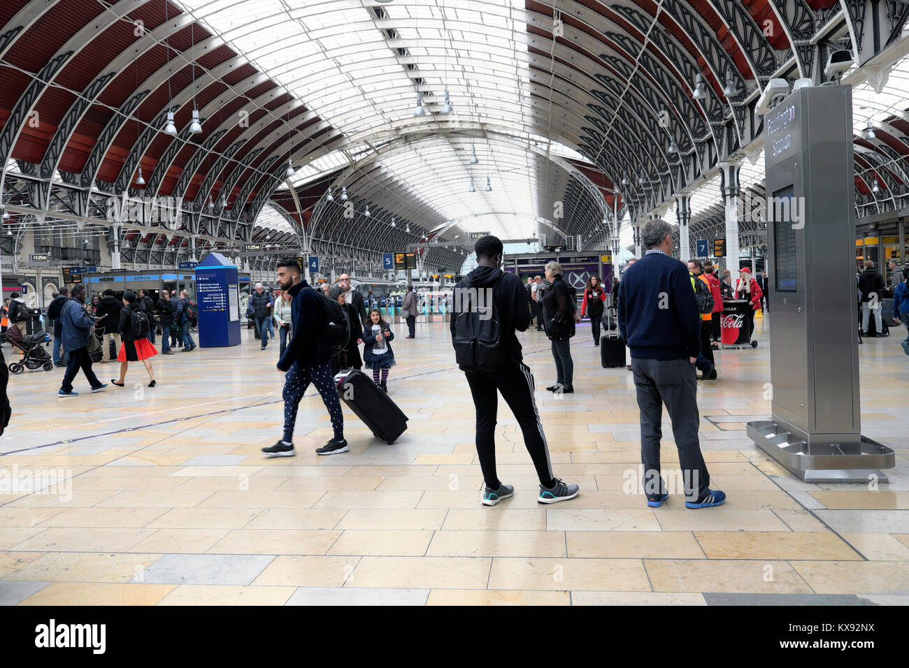 Die Menschen warten auf dem Vorplatz Bahnhofshalle mit Gepäck an der Paddington Station mit Blick auf die rood in London England UK KATHY DEWITT Stockfoto