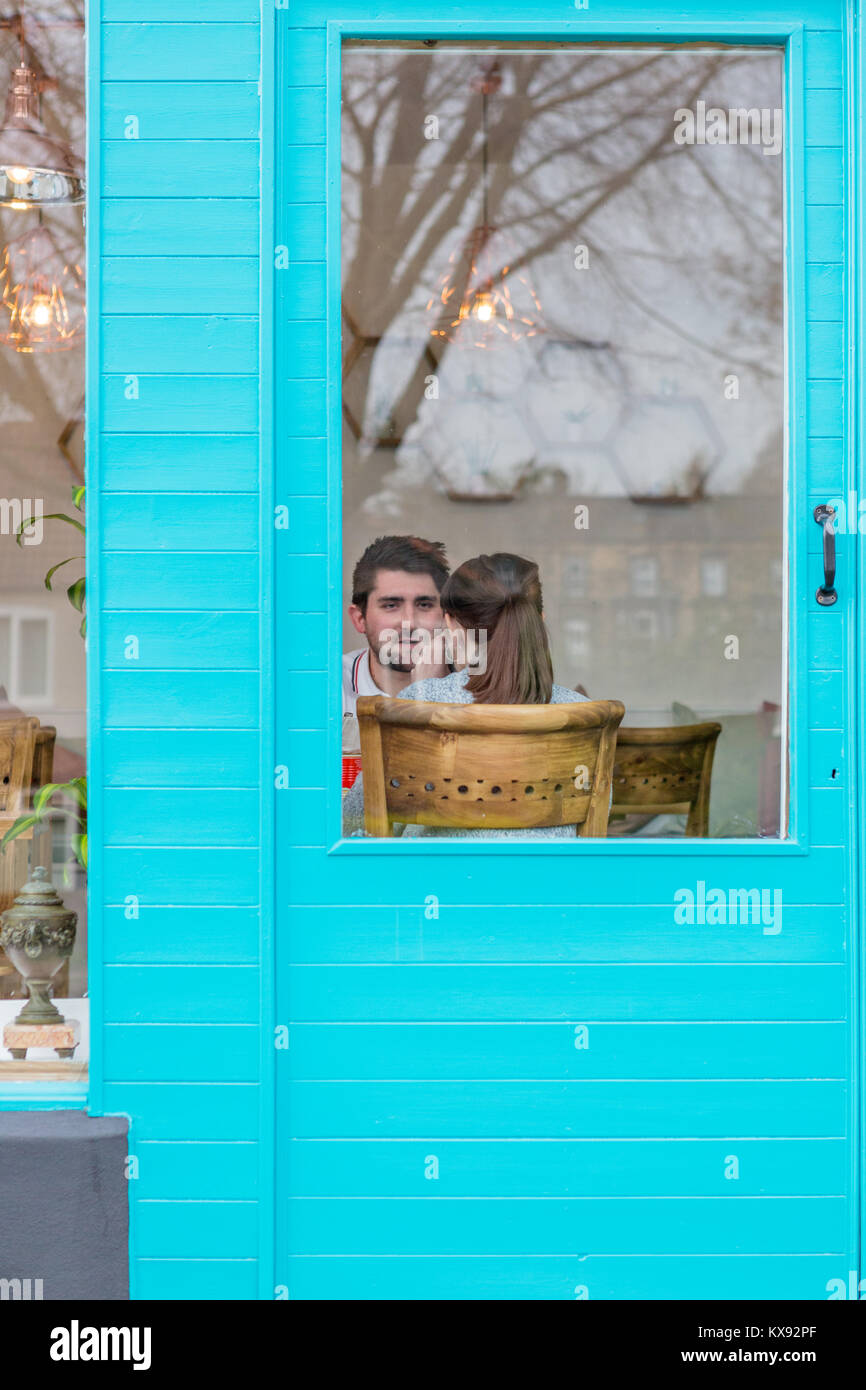 Durch die blaue Tür des jungen Paares im Gespräch Stockfoto