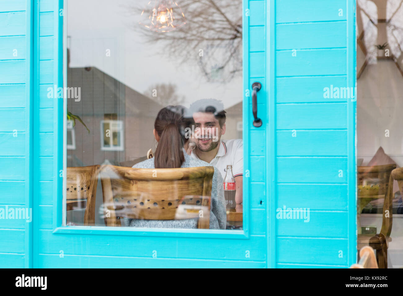 Durch die blaue Tür des jungen Paares im Gespräch Stockfoto