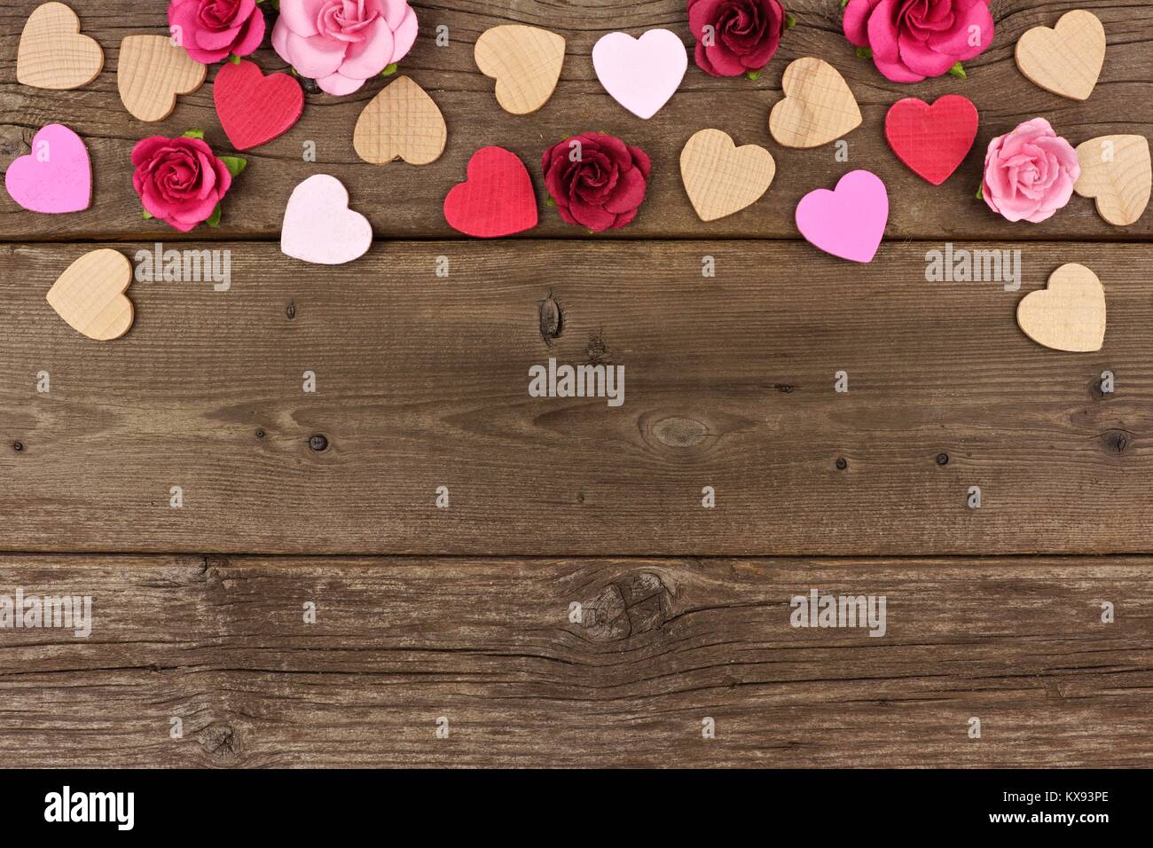 Valentines Tag oberer Rand von Herzen aus Holz und Papier Rosen gegen eine rustikale Holz Hintergrund mit kopieren. Stockfoto