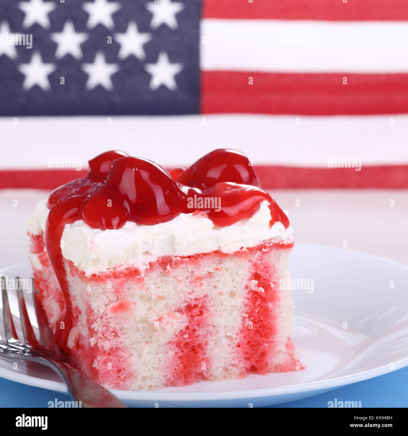 Stück Kuchen mit Kirschen auf einem Teller mit der amerikanischen Flagge im Hintergrund Stockfoto