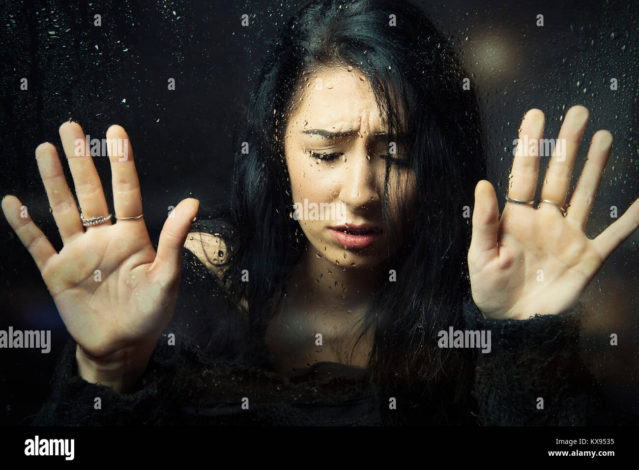 Distressed traurig deprimiert unglückliche Frau Hände gedrückt gegen Fenster nach unten schaut bei regnerischen Fenster filmische Nahaufnahme portrait Stockfoto