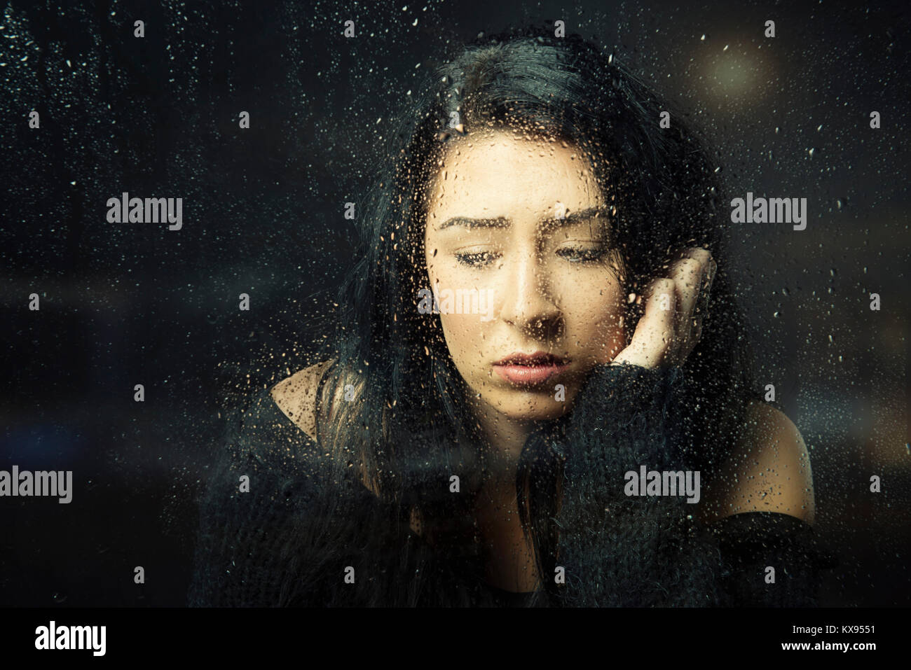 Traurig depressiven Frau, die Hand auf dem Gesicht sitzt an verregneten Fenster closeup filmischen Porträt Stockfoto