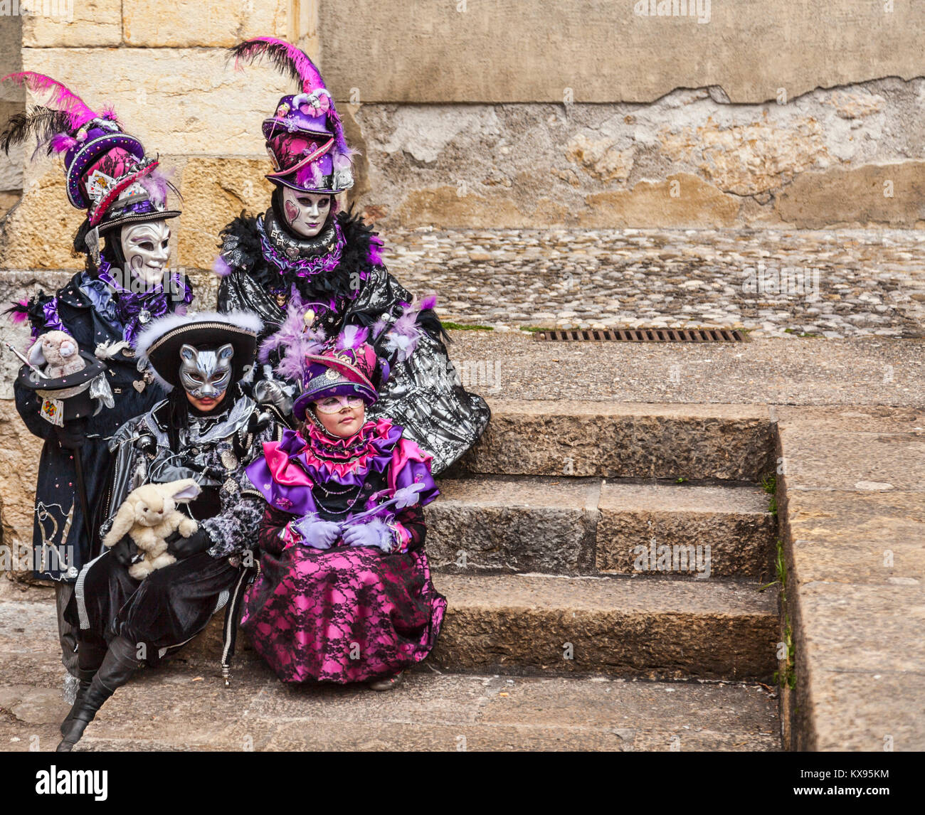 Annecy, France-March 15,2014: Vier verschleierte Personen sitzen auf Steine Schritte während der annecy Venezianischen Karneval. Jährlich in Annecy, Frankreich ist eine Ader statt Stockfoto