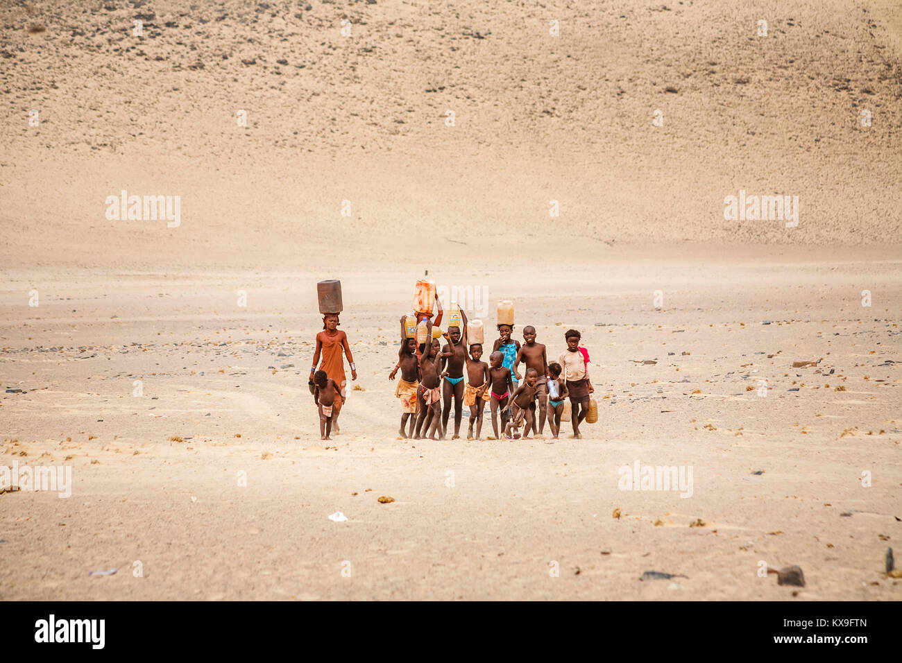 Frau Himba und Kinder arbeiten, die Wasser in ein Dorf der Himba Volk in der Kunene Region, Namibia, im Südwesten von Afrika Stockfoto