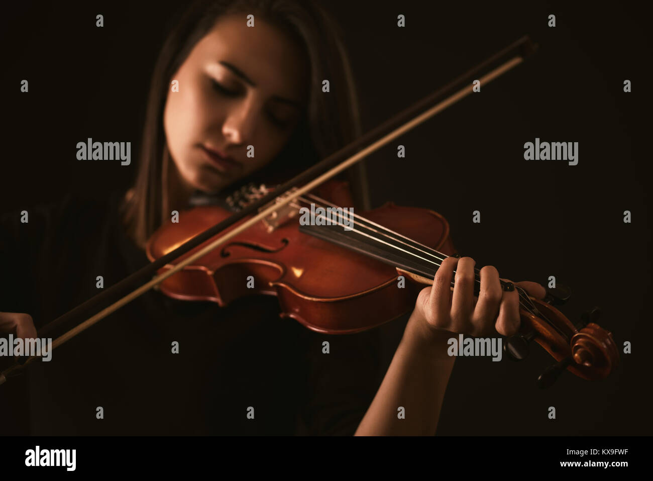 Schöne junge Frau spielt eine Violine auf schwarzem Hintergrund Stockfoto