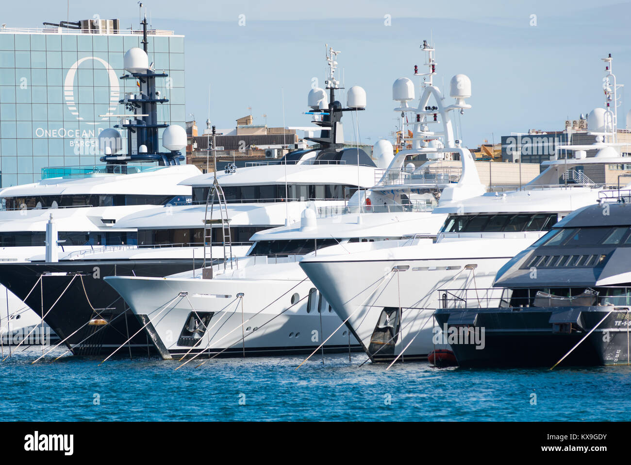 Luxus-Yachten und Cruiser vertäut im Port Vell, Barcelona, Katalonien, Spanien. Im Hintergrund ist der "One Ocean Port Vell" Mehrfamilienhaus. Stockfoto