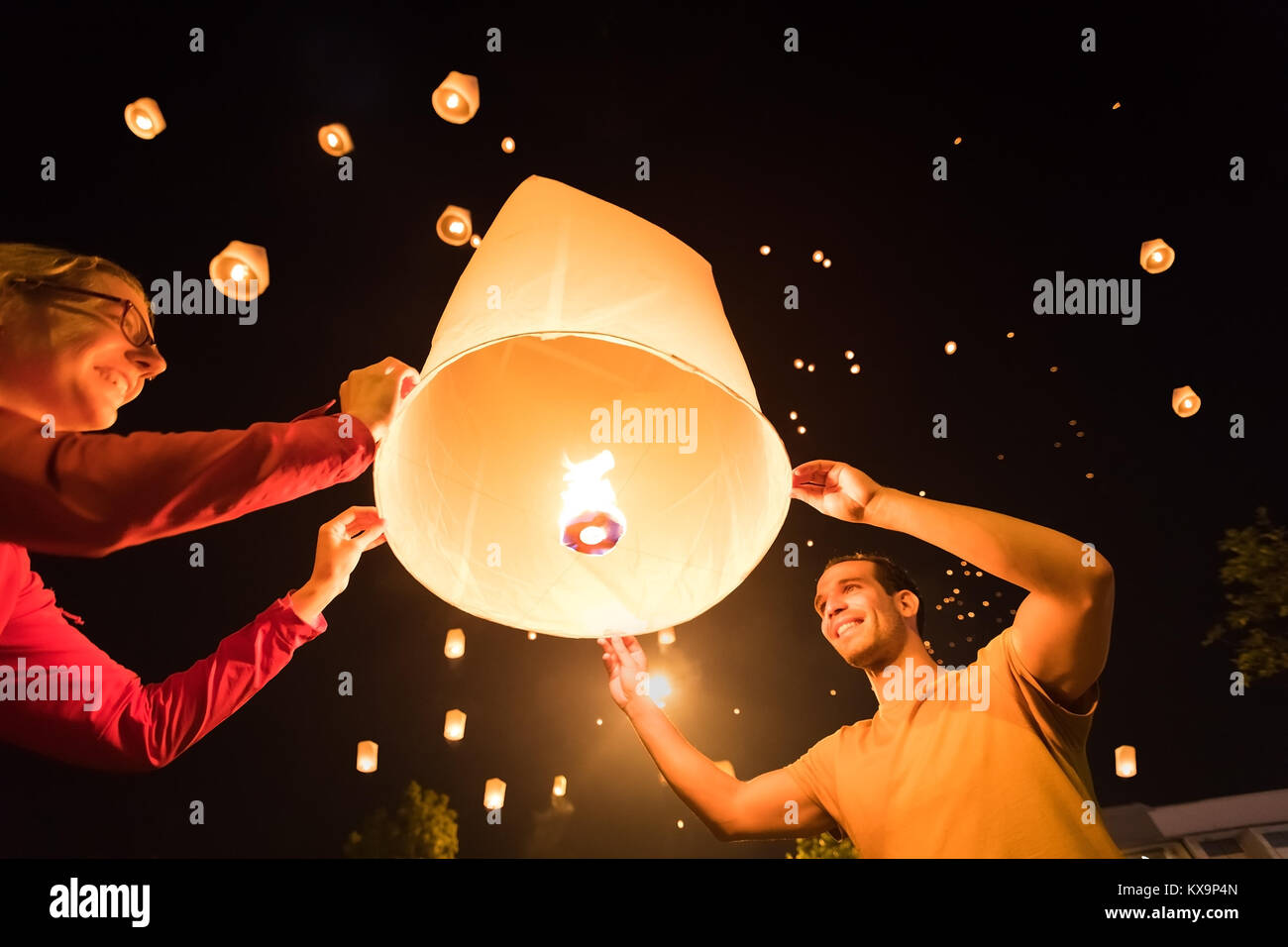 Zwei Personen Freigeben einer traditionellen fliegende Laterne an Yi Peng-/Loy Krathong Festival in Chiang Mai, Thailand Stockfoto