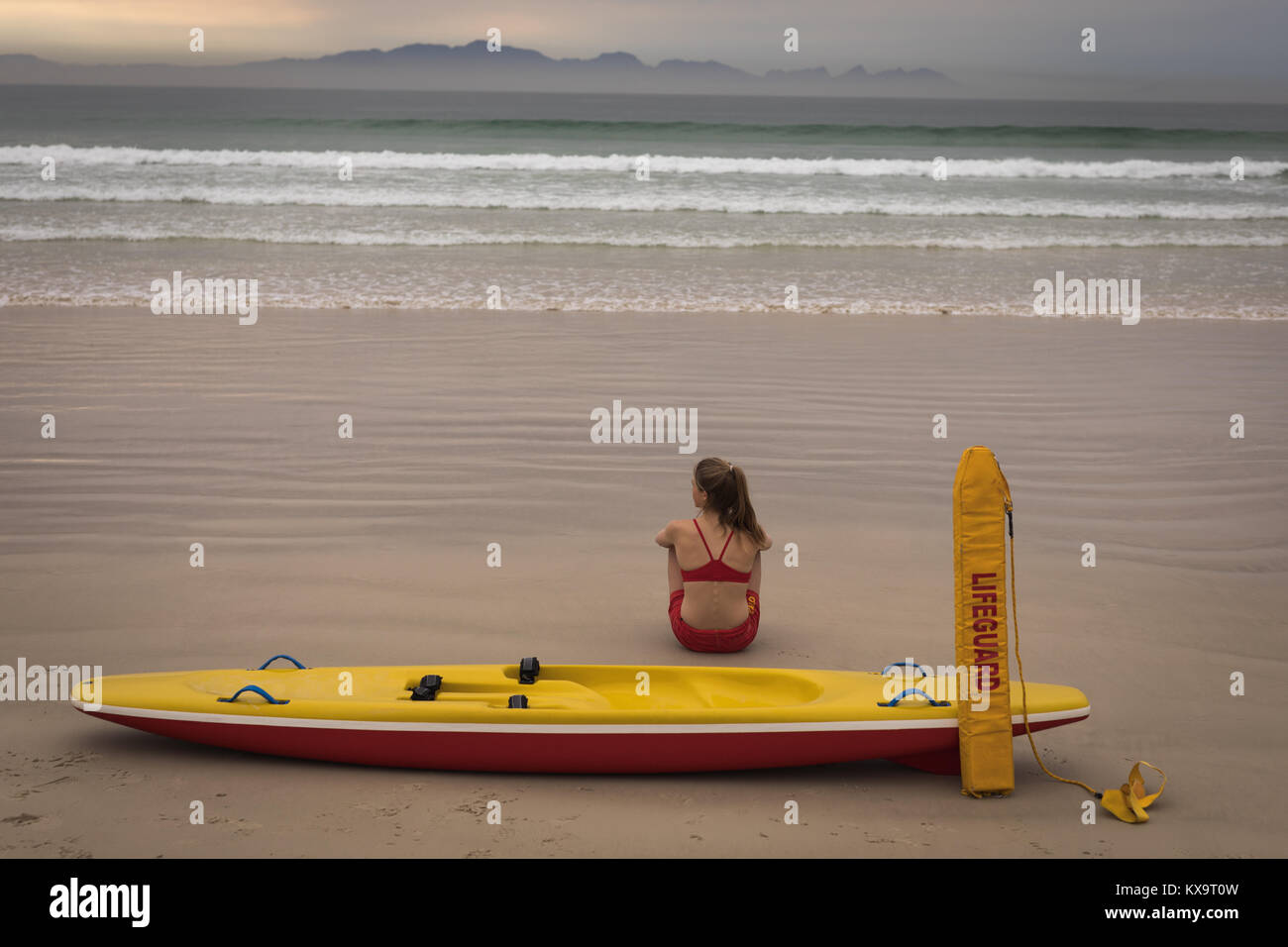Weibliche Rettungsschwimmer am Strand zu sitzen mit einem Rettungsboot und Schwimmstellung Stockfoto