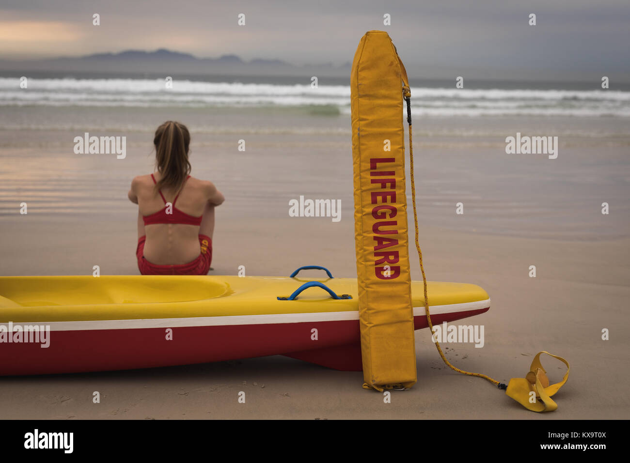 Weibliche Rettungsschwimmer am Strand zu sitzen mit einem Rettungsboot und Schwimmstellung Stockfoto