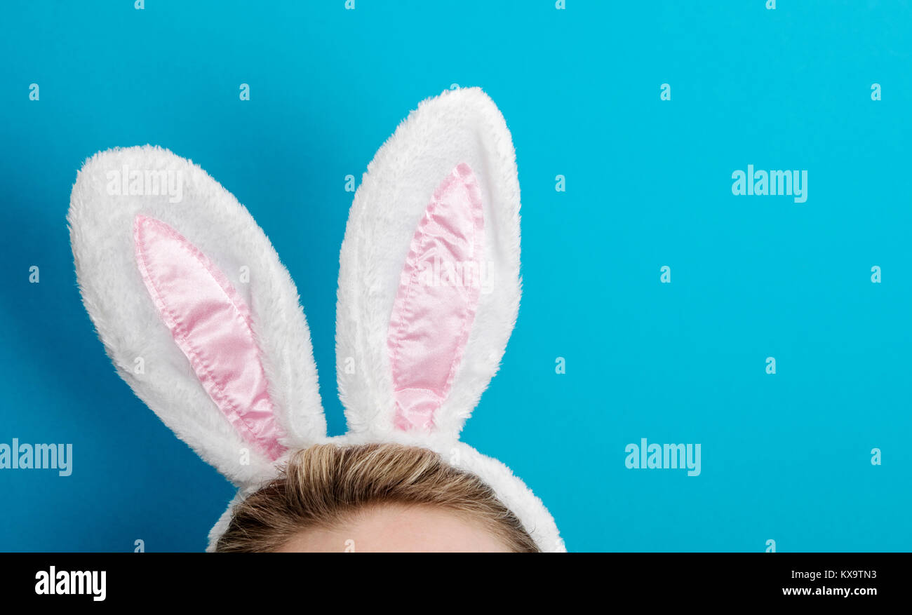 Osterhasen Ohren. Frauen tragen weiße Hasenohren Kostüm gegen einen hellen  Hintergrund blau Stockfotografie - Alamy