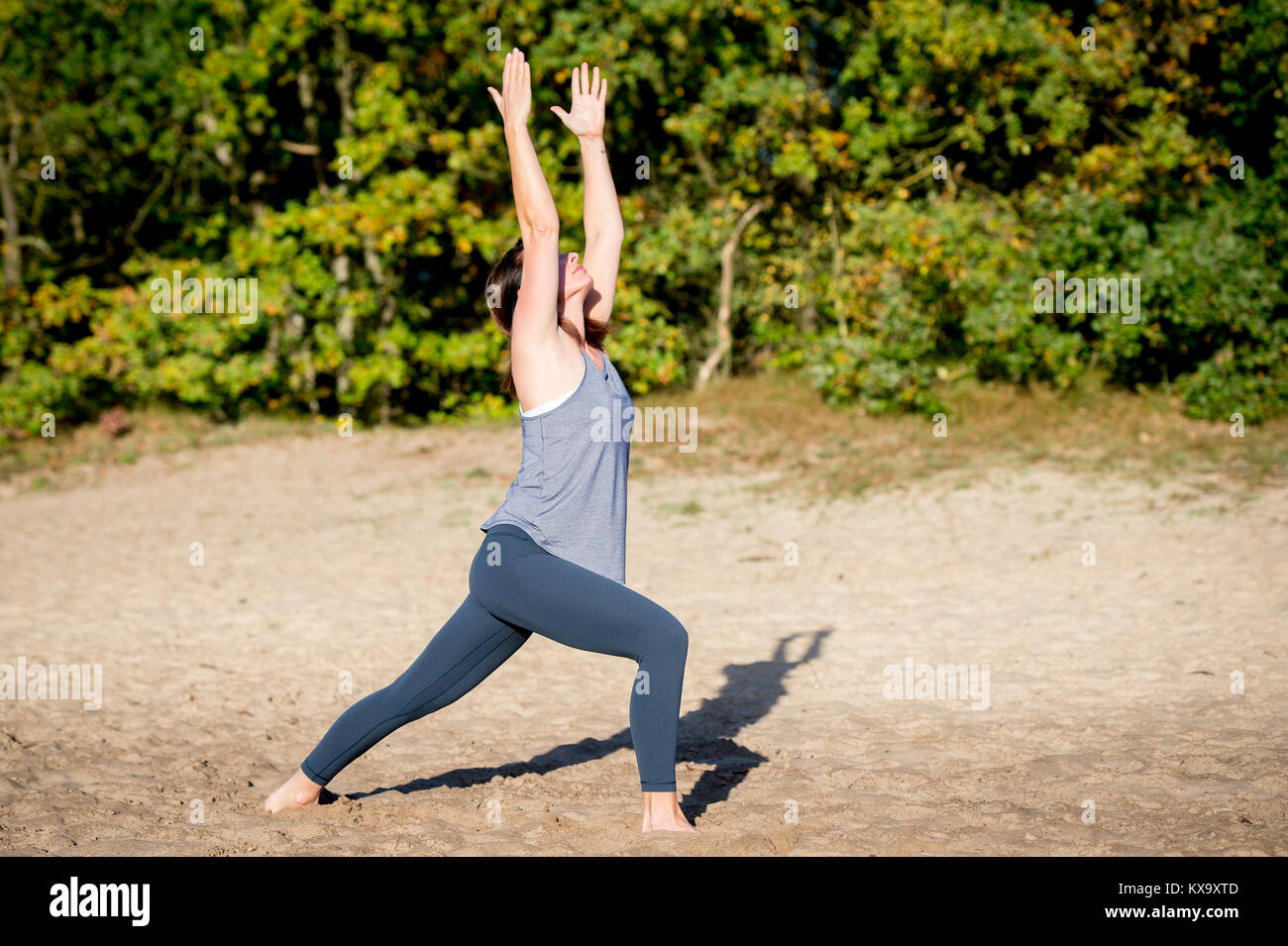 Frau Yoga in den Sand - Krieger 1 Pose-Virabhadrasana I-Herbst Tag Stockfoto