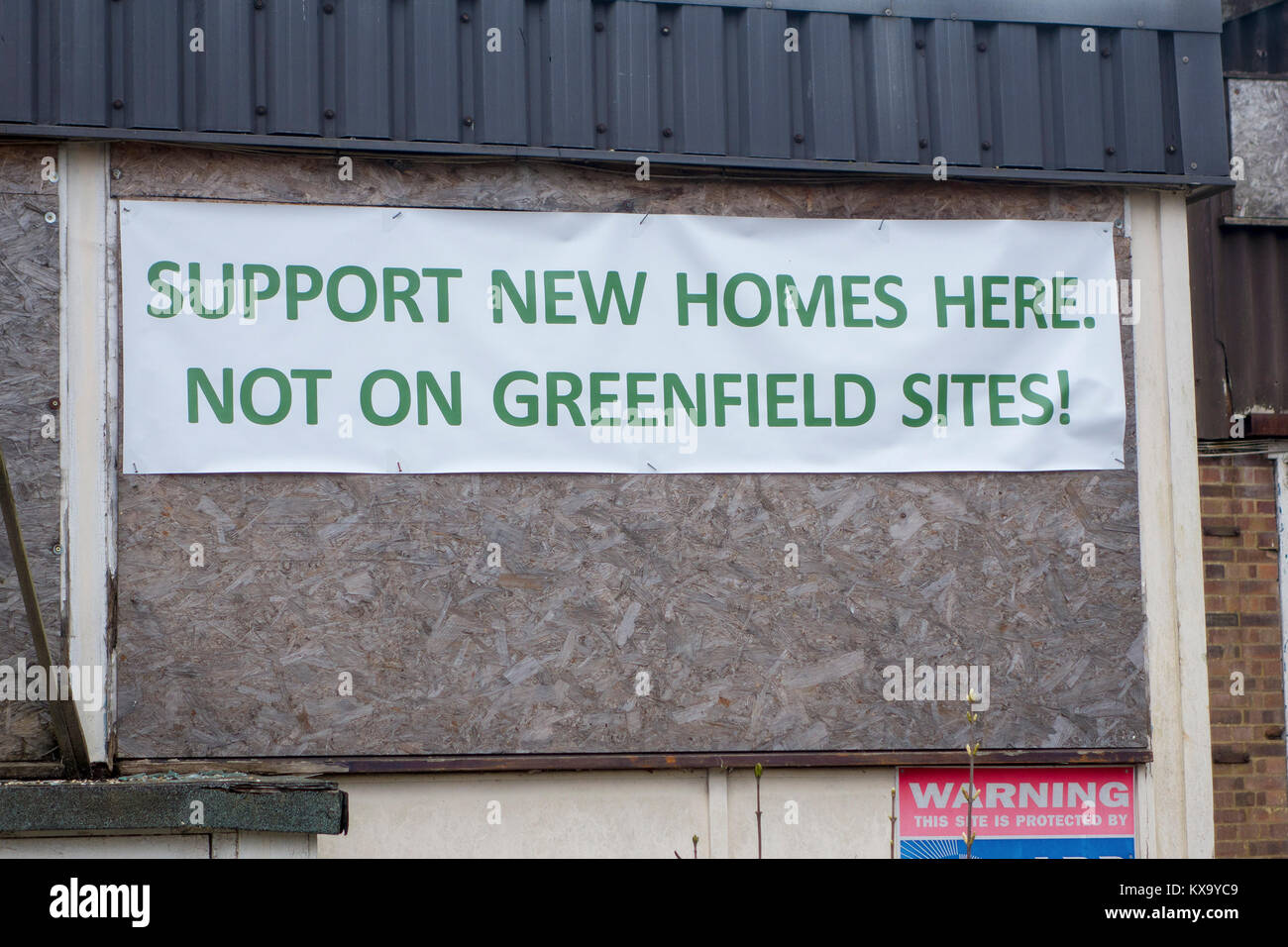 Unterstützung neuer Häuser hier, nicht auf der grünen Wiese protest Banner auf verfallene Gebäude Stockfoto