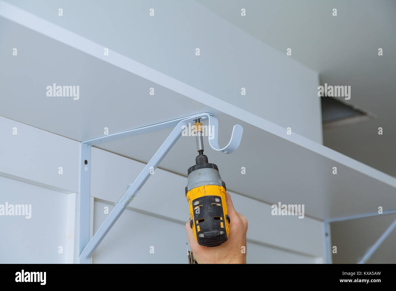 Ansicht der Rückseite ein Heimwerker mit einer Bohrmaschine ein Regal an der Wand ein Regal zu installieren. Stockfoto