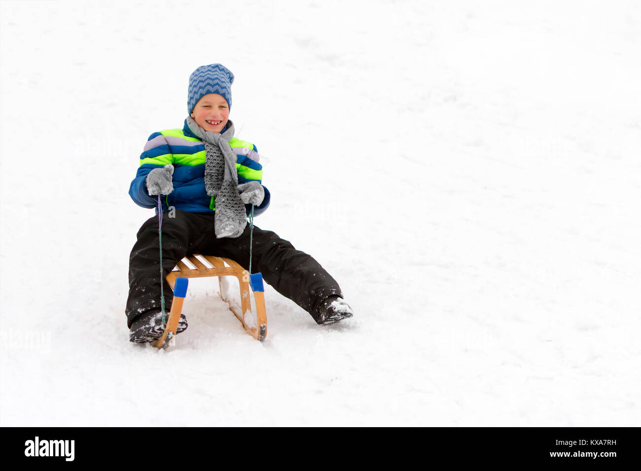 Kid Schiebetüren mit Schlitten im Schnee. Stockfoto