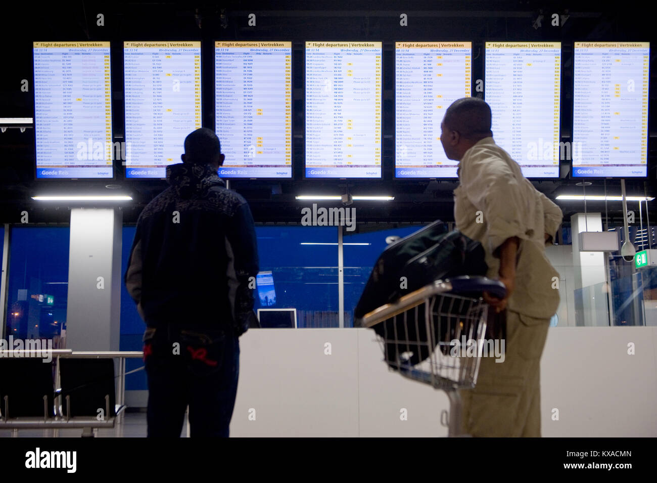 AMSTERDAM, NIEDERLANDE, 27.Dezember, 2017: Zwei Männer betrachten die Datenbildschirme seinen Flug am Flughafen Schiphol bei Amsterdam zu prüfen. Stockfoto