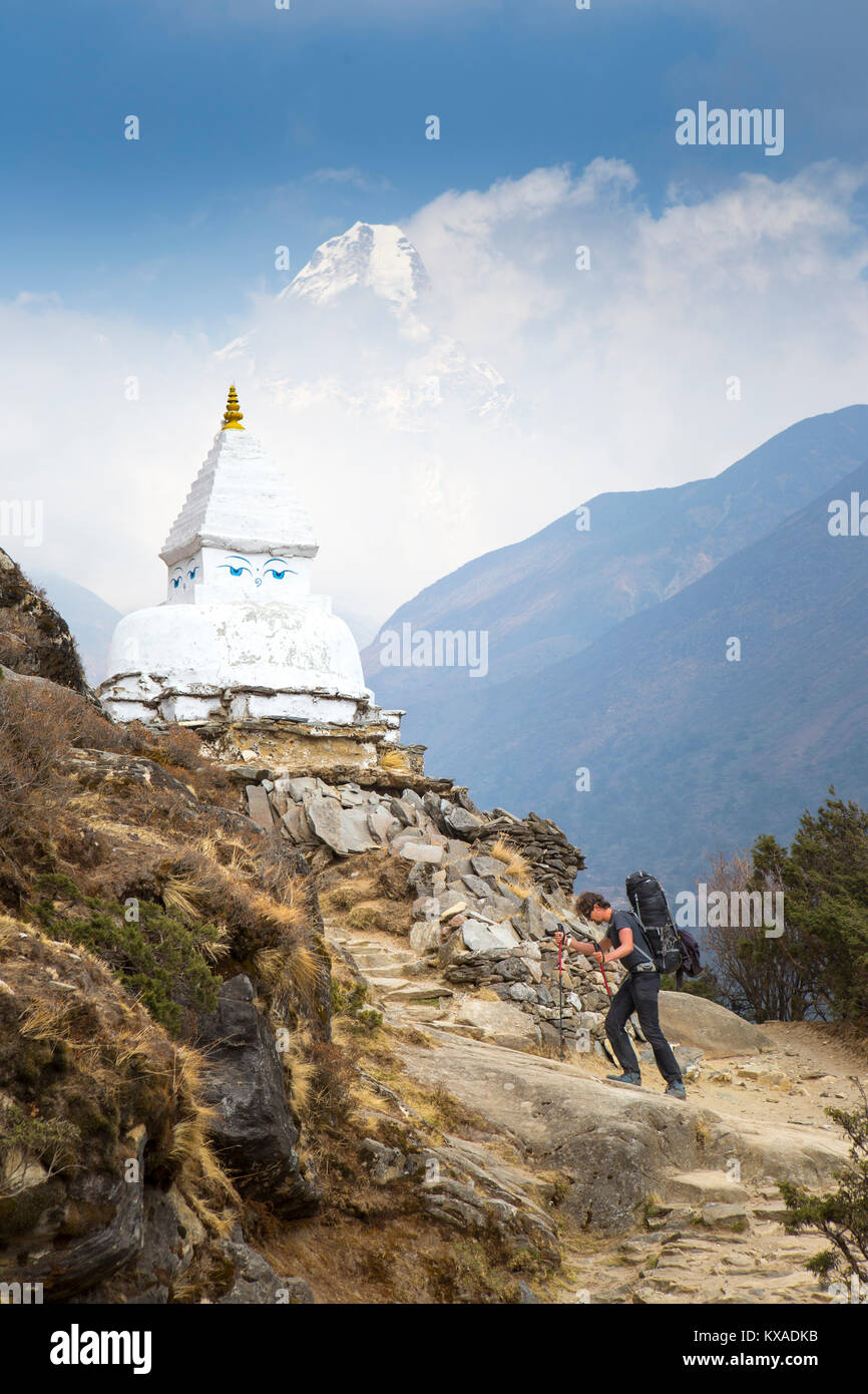 Ein Wanderer in der Nähe von eine buddhistische Stupa mit den Augen des Buddha bemalt. Im Hintergrund der Berg Ama Dablam. Stockfoto