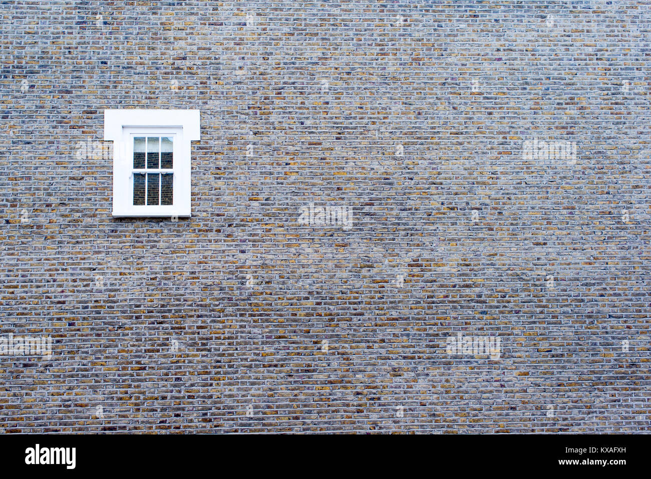Kleine weiße Fenster auf einem großen Stein leere Wand Stockfoto