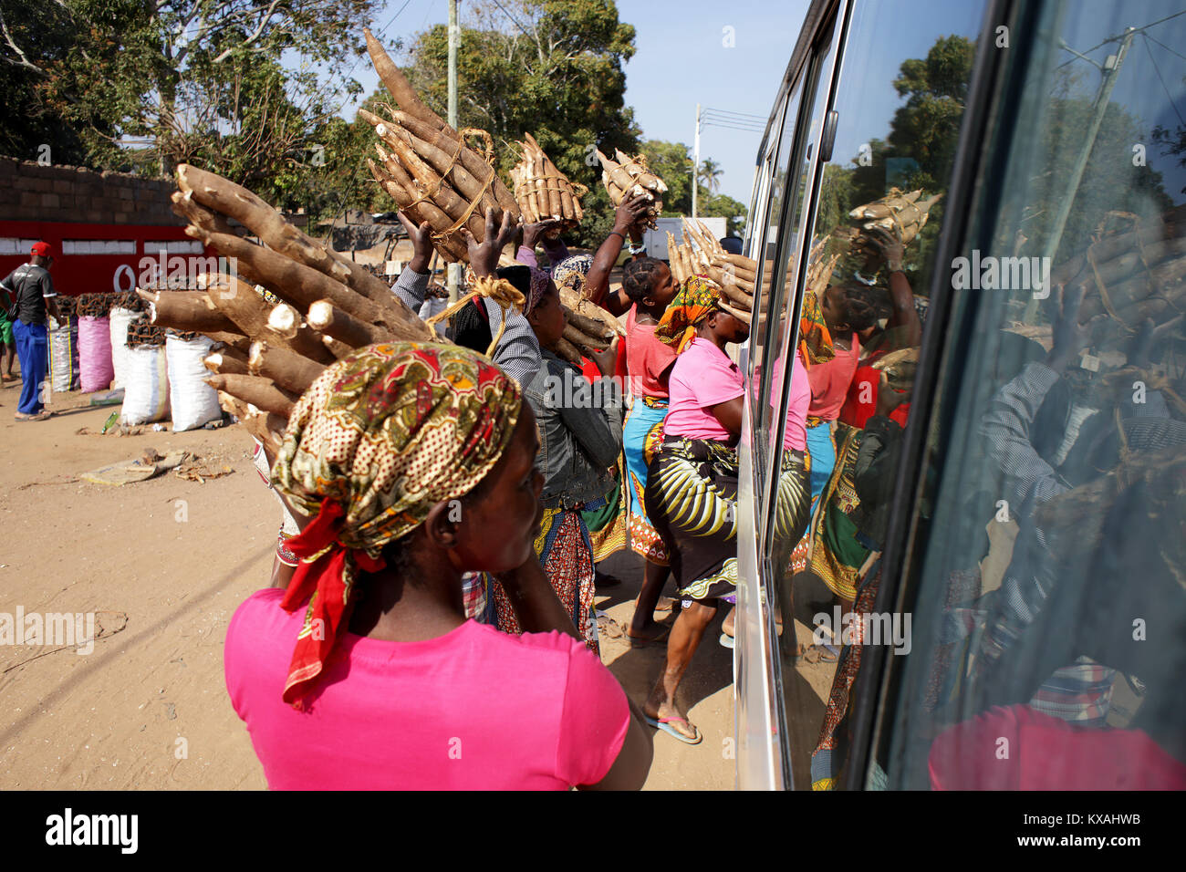 Frauen verkaufen Bündel von Wurzeln zu Menschen warten im Bus vorbei an afrikanischen Stadt, Mosambik Stockfoto