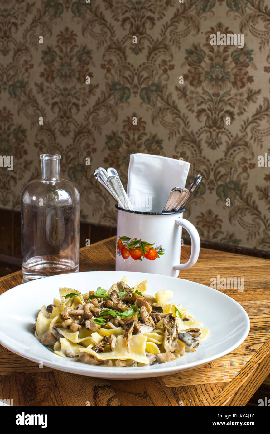 Platte von Rindfleisch Stroganoff, eine Flasche Wasser und Besteck in Becher auf hölzernen Tisch, Portland, Oregon, USA Stockfoto