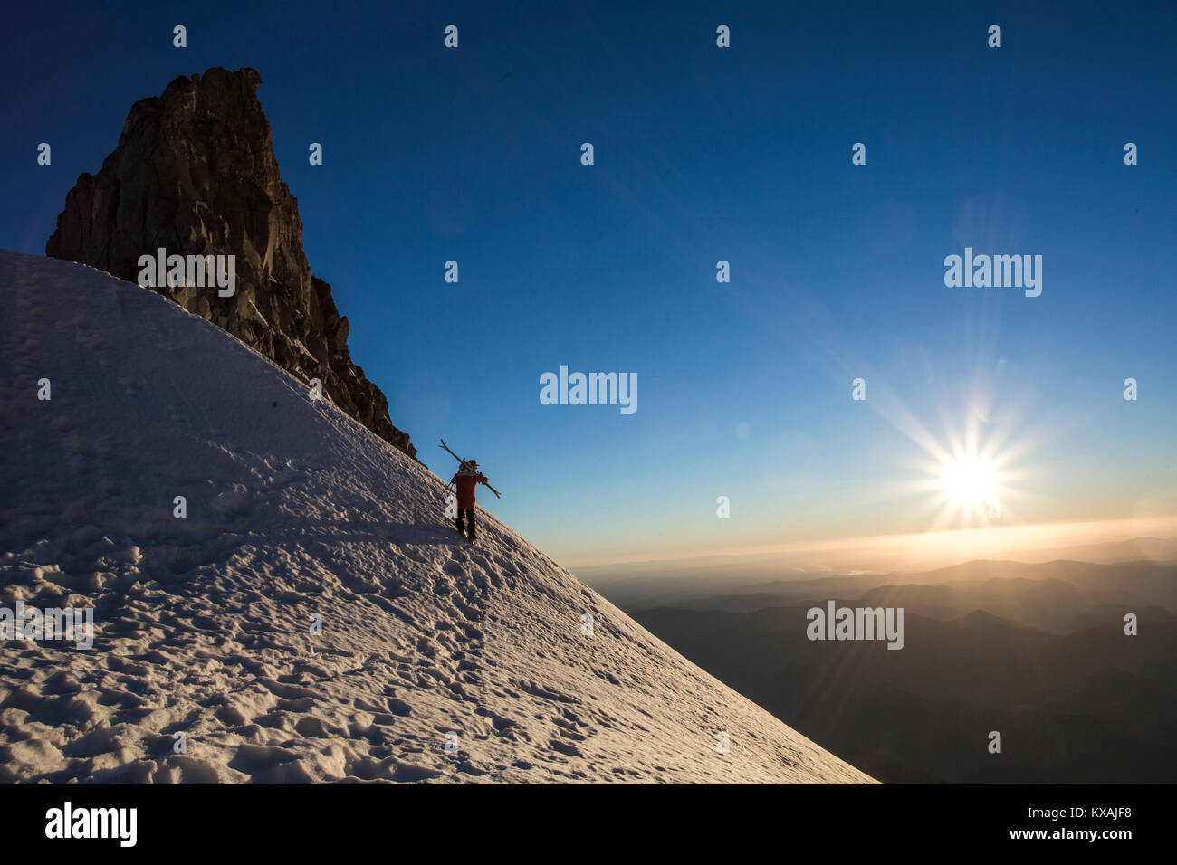 Skifahrer mit Ski auf verschneiten Berg mit Sonnenuntergang im Hintergrund, Mount Hood, Oregon, USA Stockfoto