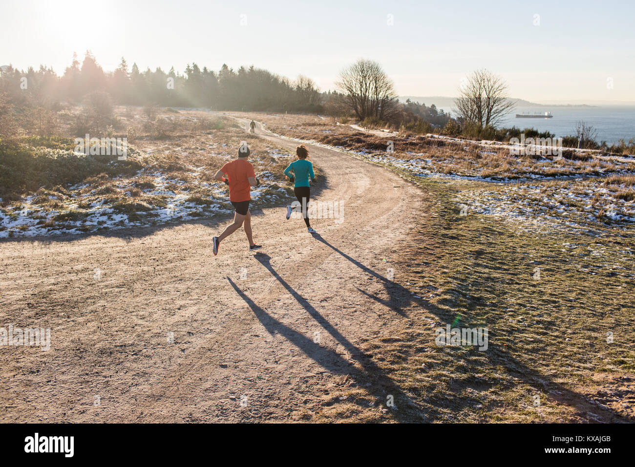 Mann und Frau joggen auf Feldweg im Winter, Discovery Park, Seattle, Washington State, USA Stockfoto