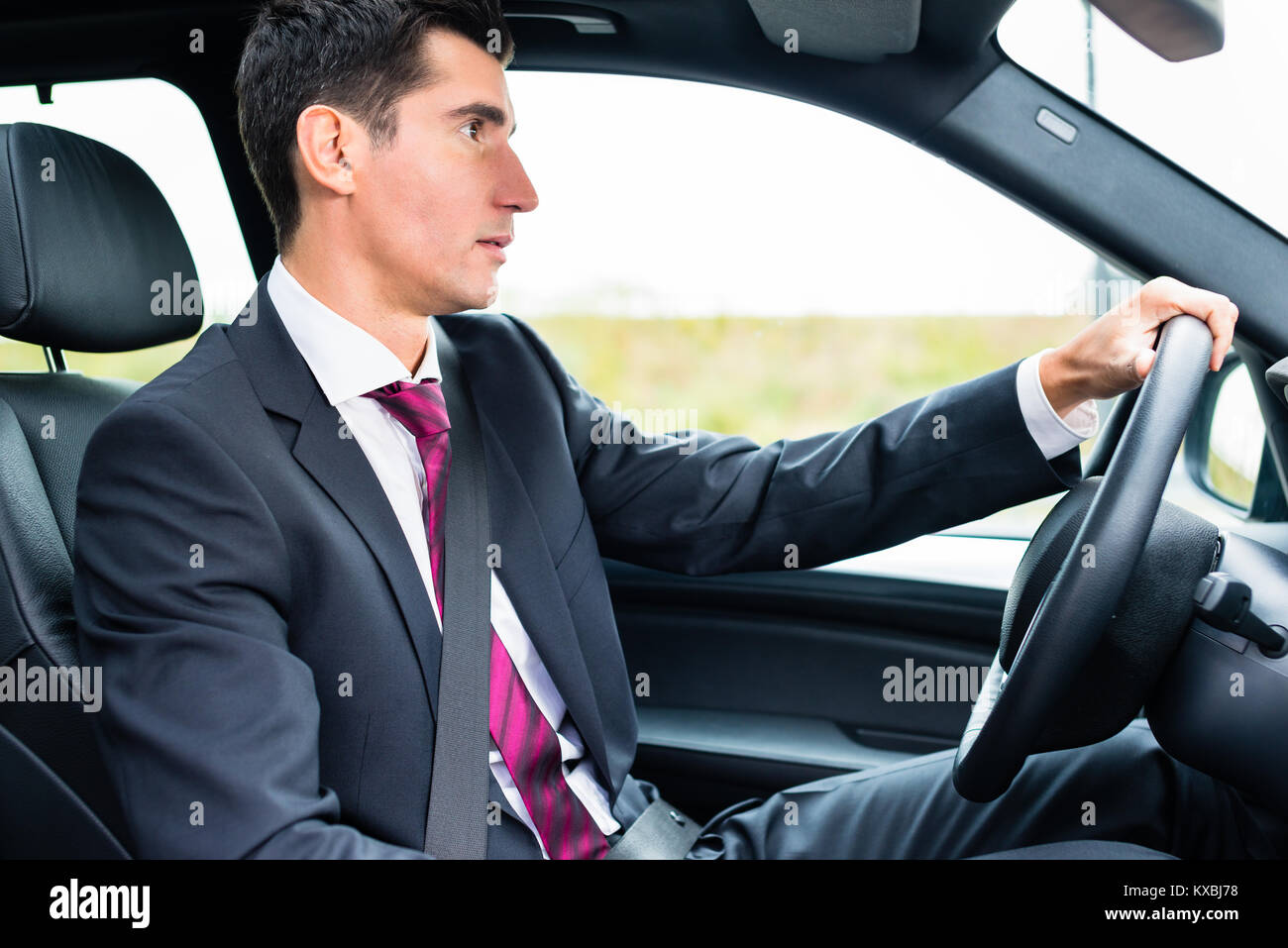 Mann, der in seinem Auto in Geschäftskleidung Stockfoto