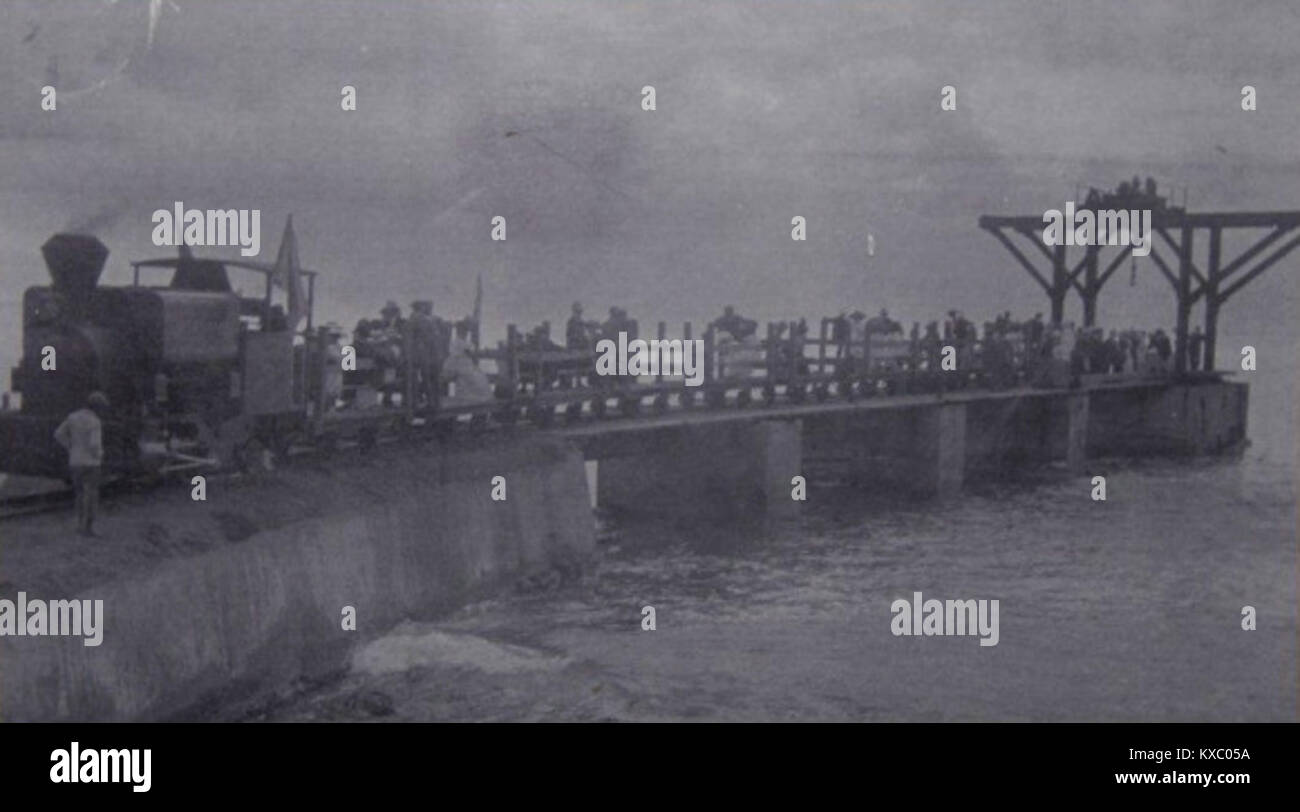 Ein historisches Schwarzweiß-Foto aus dem Jahr 1912 zeigt eine Dampflokomotive mit der Aufschrift Nr. 3 „Queen Mary“, die am Fabrikpier einer Zuckermühle auf der Insel St. Kitts ankommt, die für den Zuckerrohrtransport gebaut wurde und heute Teil der Schmalspurbahn der Insel ist. :ContentReference[oaicite:0]{index=0} Stockfoto