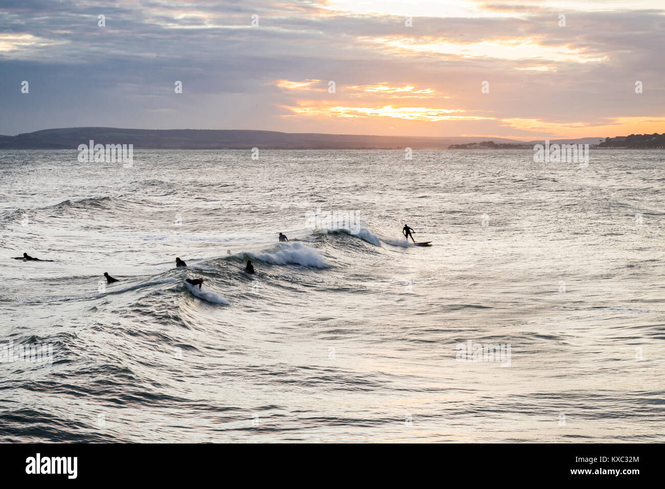 Golden Sunset über Bournemouth Strand/Meer mit Surfer Genießen der guten Swell, Bournemouth, Dorset, England, Großbritannien Stockfoto