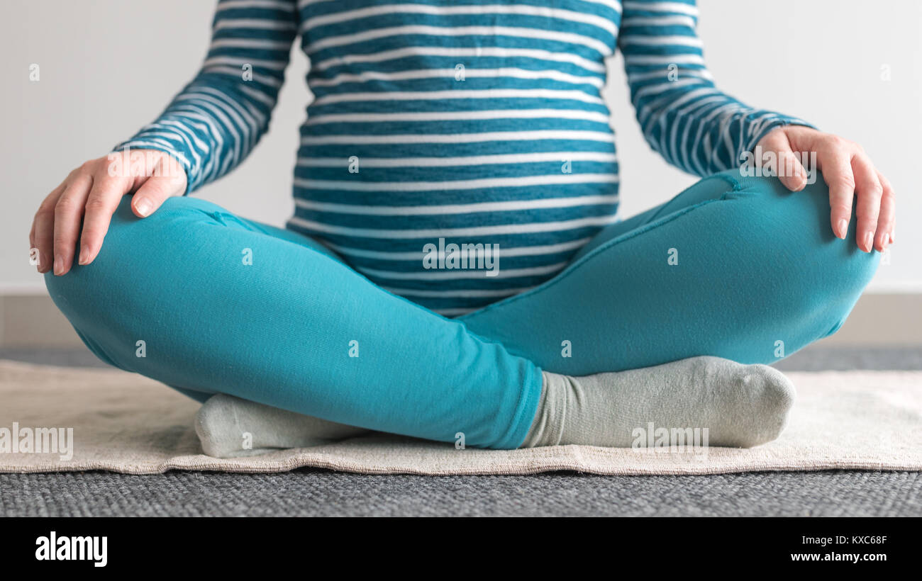 Schwangeren Yoga Übung zu Hause. Schwangerschaft Yoga und drinnen Fitness Concept. Unbenotete kontrastarmen Aufnahmen mit natürlichen Fenster Licht. Stockfoto