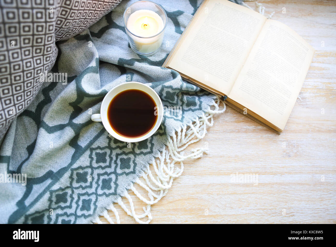 Tasse Kaffee, Kerze und Buch auf dem Holzboden Stockfoto