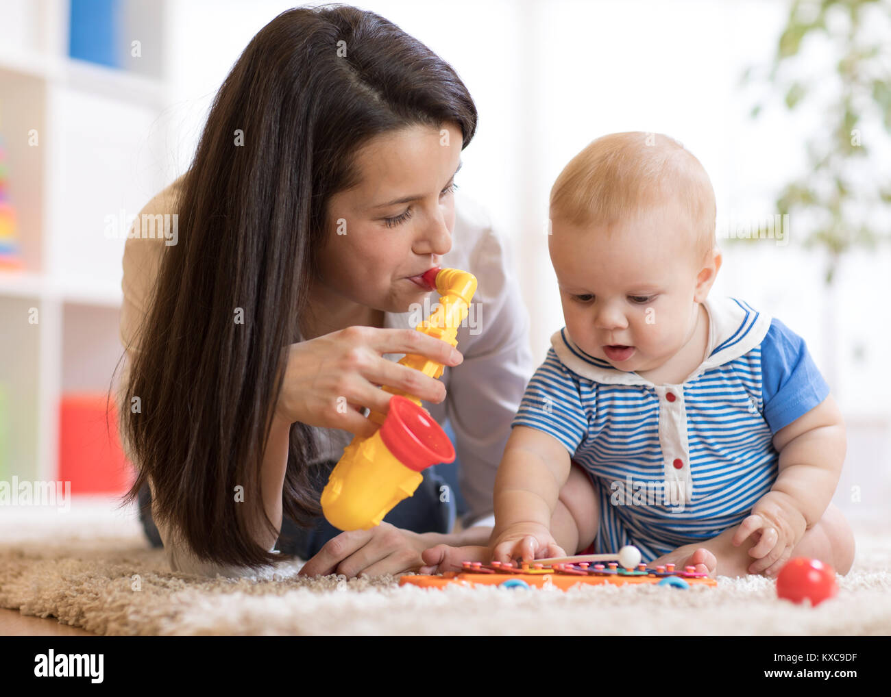 Frau und Baby spielen musikalische Spielzeug im Kindergarten Stockfoto
