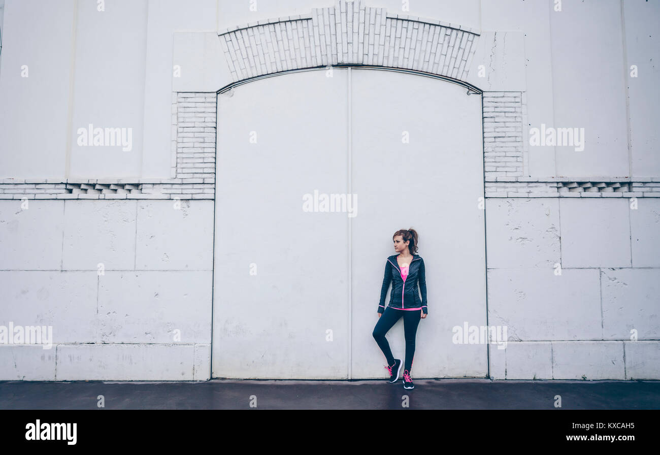 Frau mit Sportbekleidung stand vor der weiße Tür Stockfoto