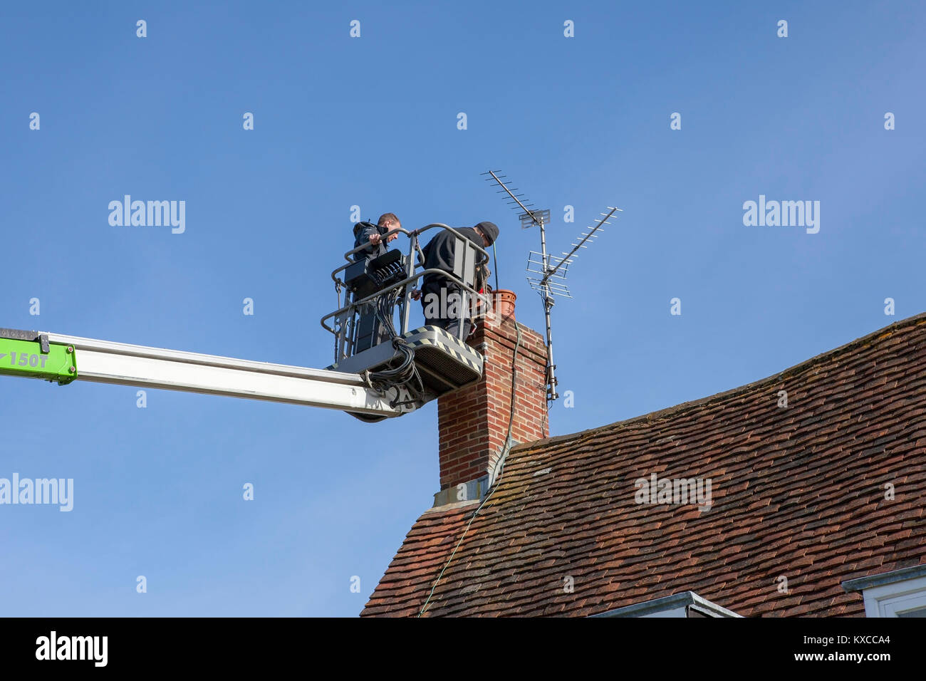 Arbeiten Männer mit einem Cherry Picker der Motorhaube an einen Kamin zu befestigen Stockfoto