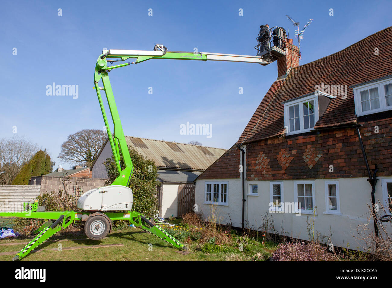 Arbeiten Männer mit einem Cherry Picker der Motorhaube an einen Kamin zu befestigen Stockfoto