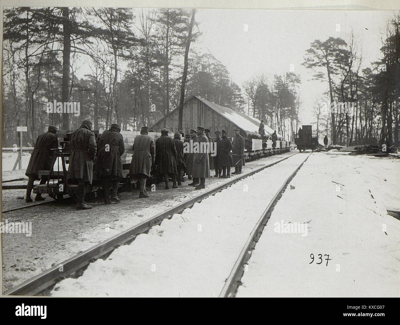 Das Bild mit dem Titel „Verladetätigkeit in Galizien“ zeigt Arbeiter, die Güter mit Kränen oder Hebezeugen auf Eisenbahnwaggons verladen, was den Transport und die wirtschaftliche Tätigkeit im historischen Galicien widerspiegelt. Stockfoto