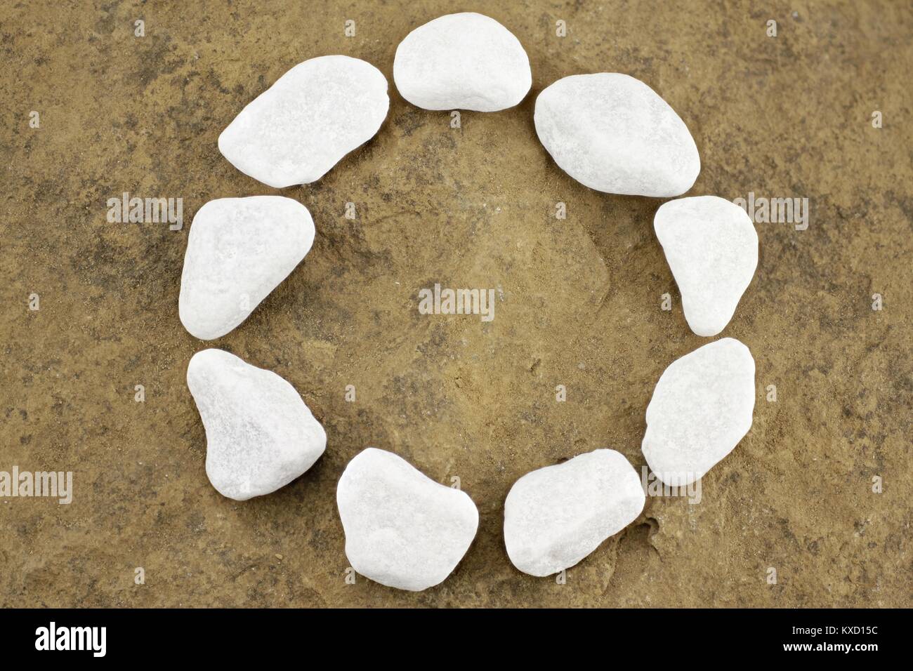 Kreis mit weißen Kieselsteinen auf braunem Stein chunk Stockfoto