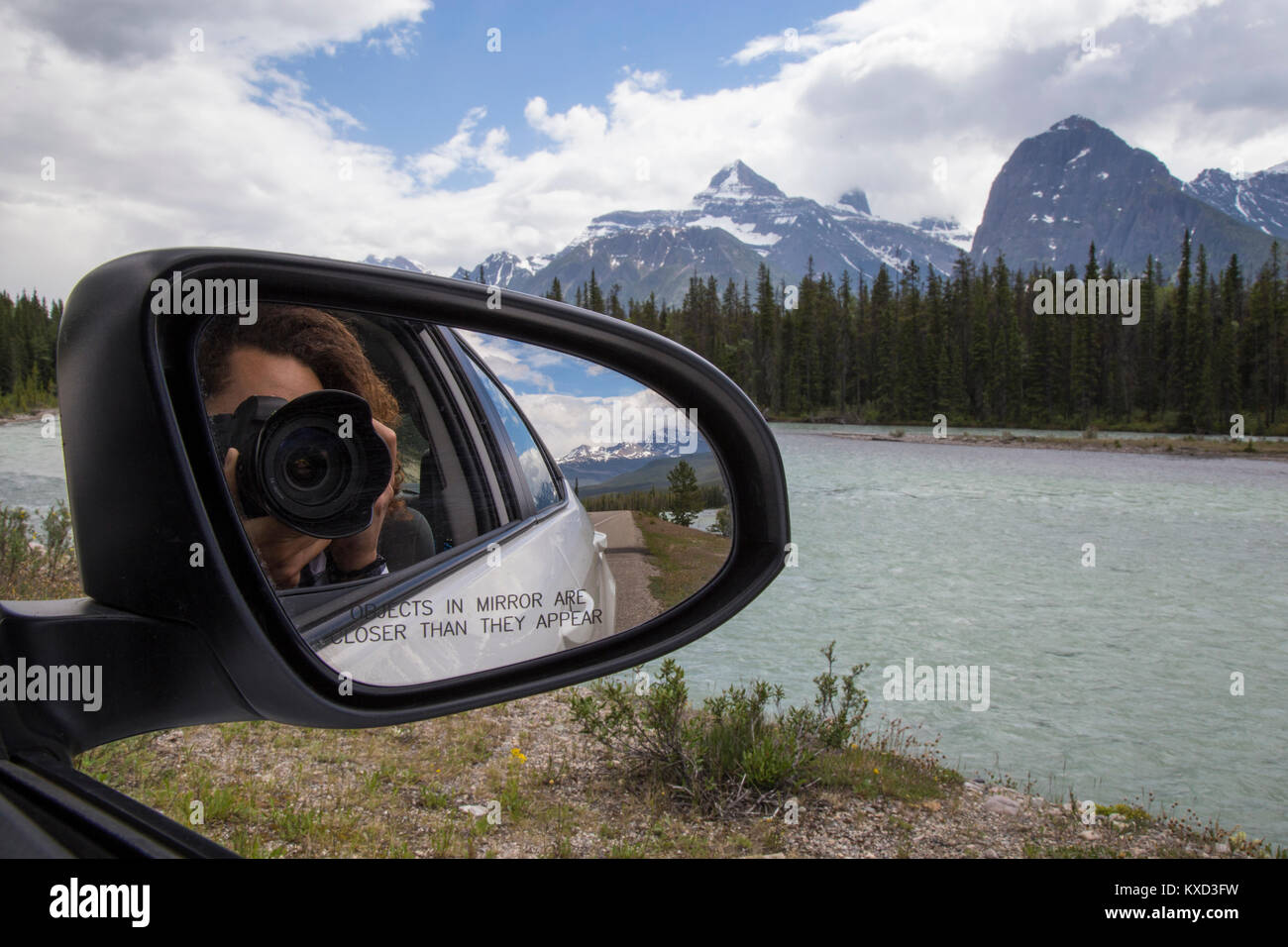 Reflexion des Menschen fotografieren mit der Kamera in der Seite gesehen Rückspiegel des Autos gegen Berge Stockfoto