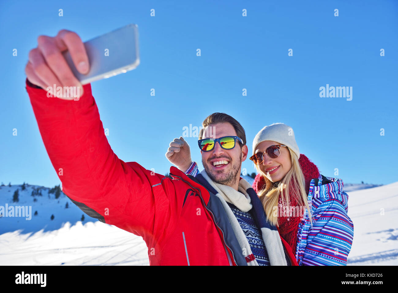 Glückliches Paar mit Smartphone selfie Stick über Winter Hintergrund Stockfoto