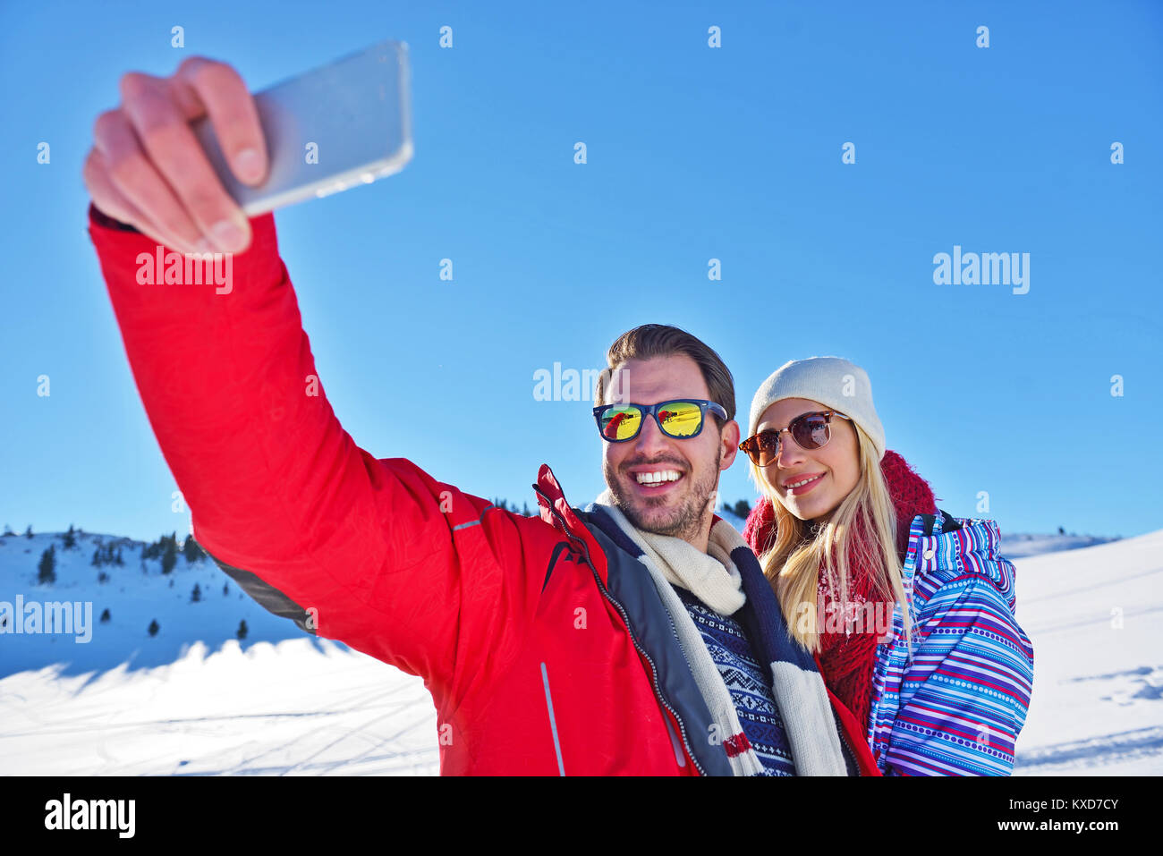 Glückliches Paar mit Smartphone selfie Stick über Winter Hintergrund Stockfoto