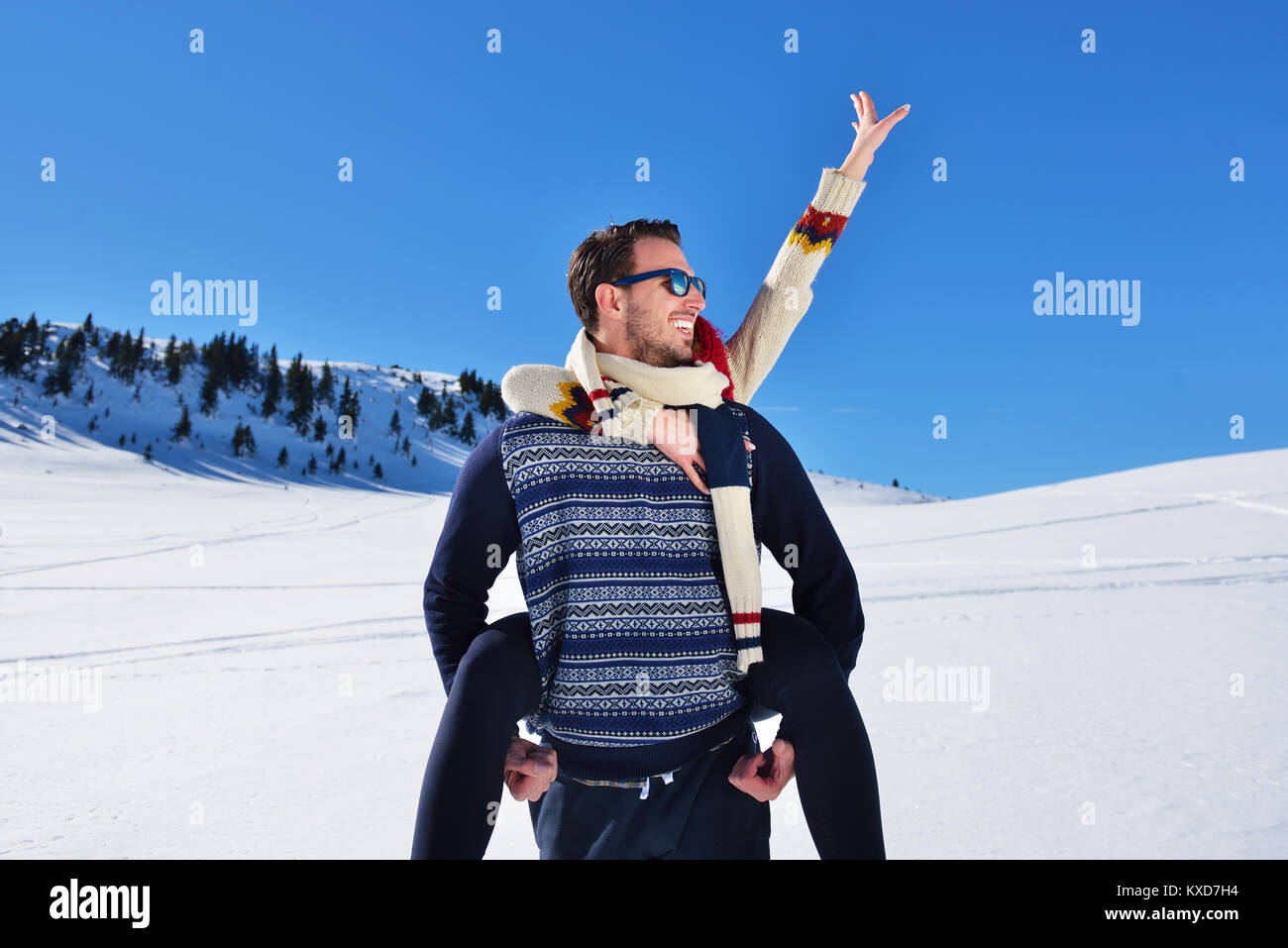 Ein junges Paar, das Spaß im Schnee. Glückliche Menschen am Berg, piggyback Ride zu sein lächelndes Freundin. Stockfoto