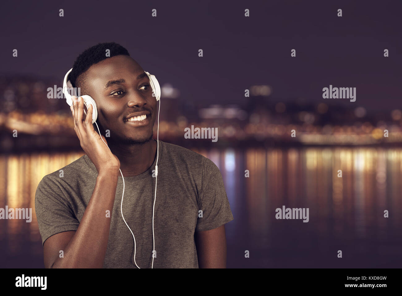 Happy afrikanischer Mann zu Fuß am Strand beim Hören von Musik über Kopfhörer. Stockfoto